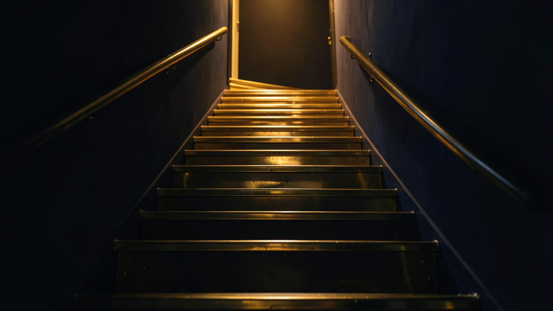 Brass steps rising towards a gold-lit academic goal